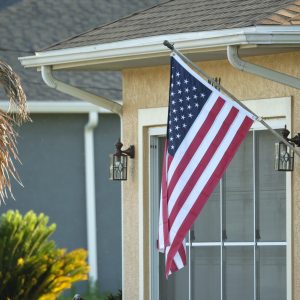 American flag waving on the corner of private residential house, symbol of patriotism.