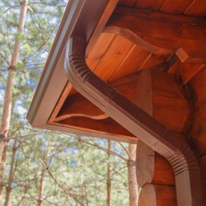 Roof gutter system on log house in forest.