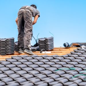workman installs a fired ceramic tile on the roof.