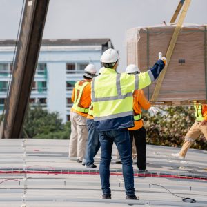 Service engineer installing solar cell on the roof of factory. Technicians working about solar panel system outdoors. Clean and Renewable energy concept.