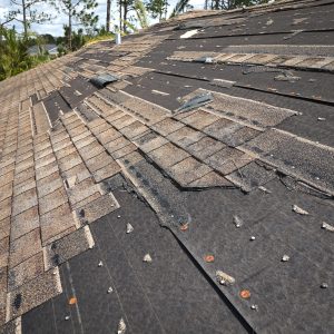 Wind damaged house roof with missing asphalt shingles after hurricane Ian in Florida. Repair of home rooftop concept